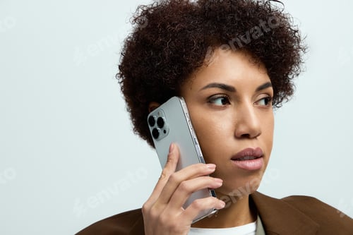 Preview: Elegant young woman engaged in a stylish phone conversation in a modern setting