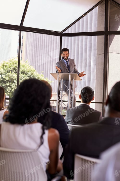 Preview: Hispanic man presents business seminar to audience, vertical