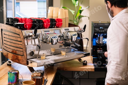 Preview: Waiter preparing coffee.Pouring milk with black gloves.He wears a mask on his face.