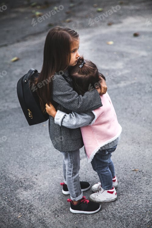 Preview: Little girls hug in the street. Stylishly dressed. Man, fashion, relationship, love