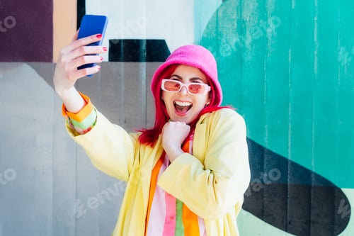 Preview: Excited pink hair woman taking a selfie photo outdoors. Emotional fashion woman taking selfie photo