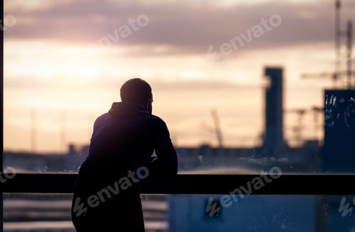 Preview: Back view of a man standing and looking through glass window of the airport building to outside.