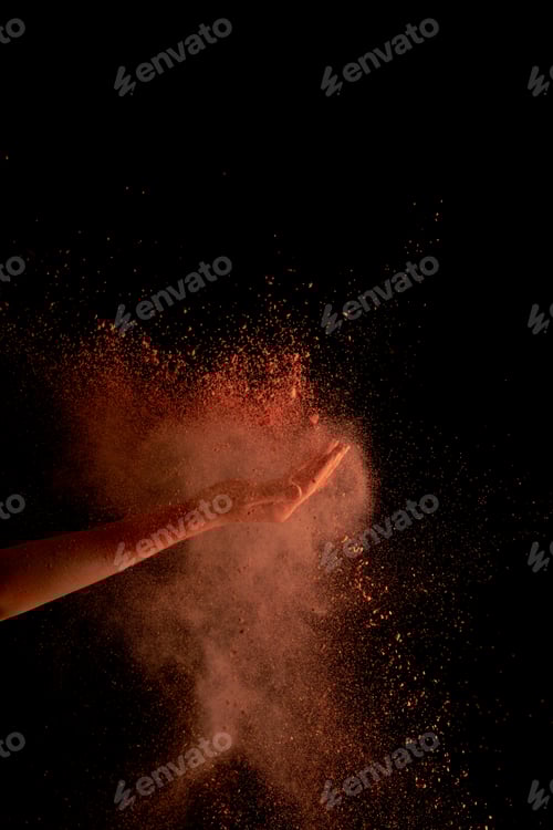 Preview: cropped view of female hand with orange colorful holi paint burst on black background
