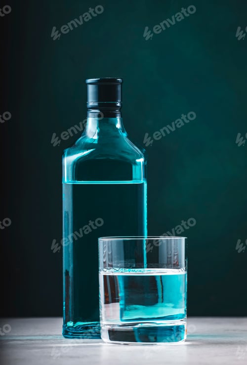 Preview: Dry gin in glass with sapphire blue bottle on dark green background