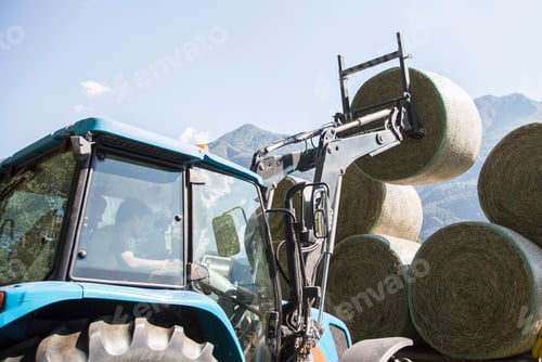 Preview: Farmer at work loading hay bales on a sunny day
