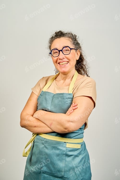 Preview: A woman wearing a blue apron and glasses is smiling