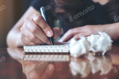 Preview: a businesswoman working and writing down on a white blank notebook with screwed up papers