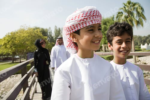 Preview: Two boys smiling outdoors on a sunny day with adults in the background