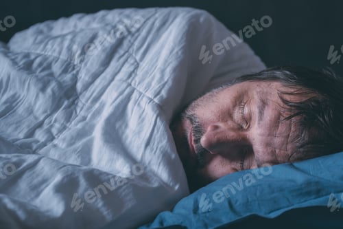 Preview: Tired asleep adult male in a bed on blue pillow