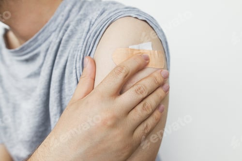 Preview: Adhesive bandage on man arm after Covid-19 vaccine injection, close up. Coronavirus Vaccination