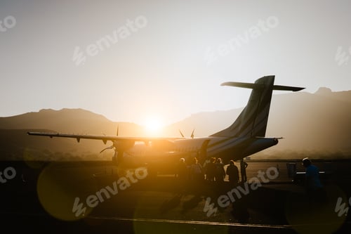 Preview: Passengers boarding to propeller aircraft on dusty morning. Mountain range surrounding runway on Sao