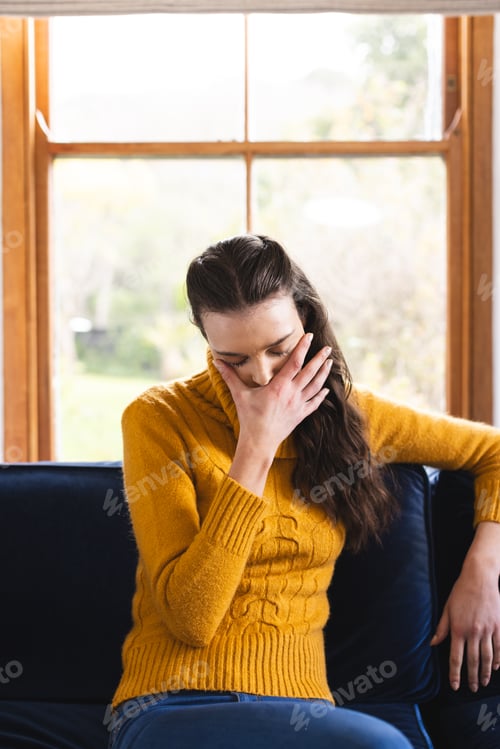 Preview: Sad caucasian woman sitting on sofa having video call at home