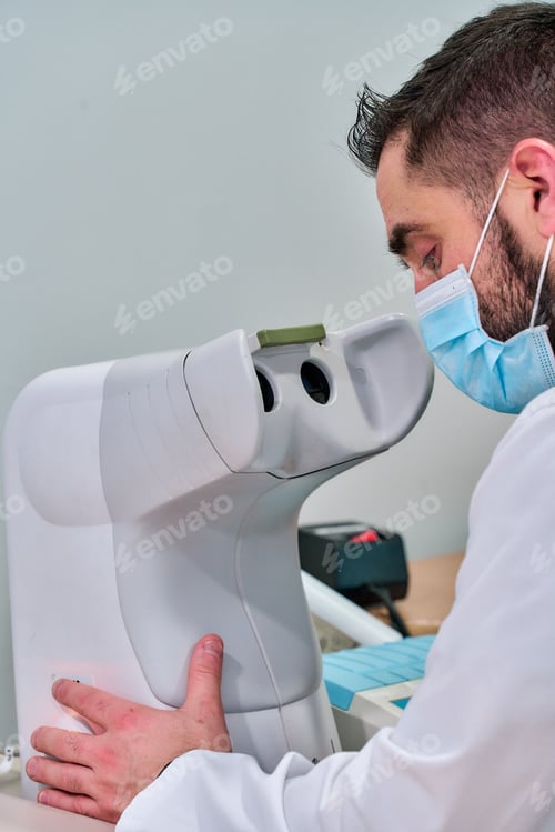 Preview: Vertical shot of a doctor working on an optometrist machine