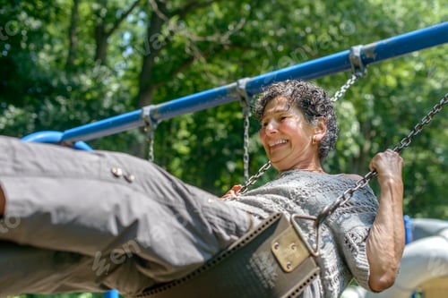 Preview: Senior woman in playing on park swing