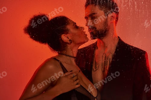 Preview: A passionate kiss behind a rain soaked glass during an intimate moment in soft red light