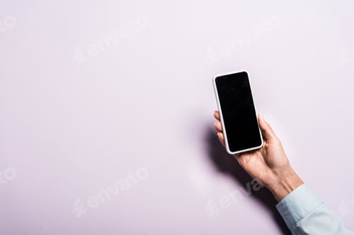 Preview: cropped view of woman holding smartphone with blank screen on purple