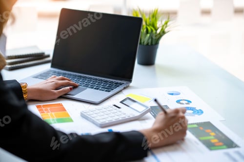 Preview: Asian businesswoman working on laptop and taking notes at the office
