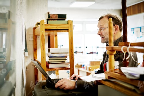 Preview: A man using a laptop computer on a bookbinding business.