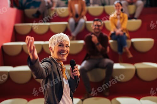 Preview: Businesswoman giving the lecture to her colleagues, using a microphone.