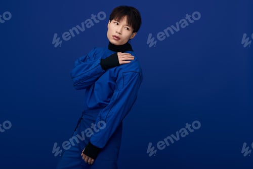 Preview: Handsome young asian man poses elegantly against a vibrant blue backdrop in stunning attire