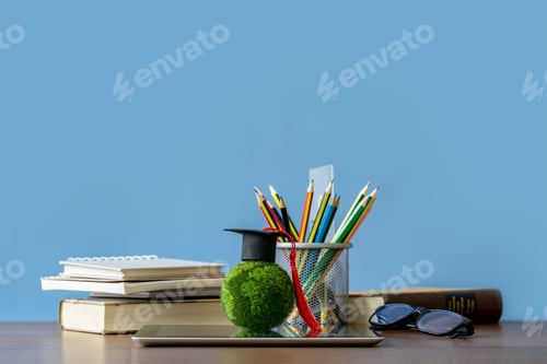 Preview: Graduation day.Education learning concept.A mortarboard on green earth with stack of books.