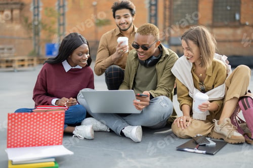 Preview: Students watching something on laptop on asphalt