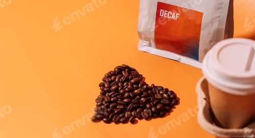 Preview: Coffee beans in the shape of a heart on an orange background next to packaging with text decaf and a