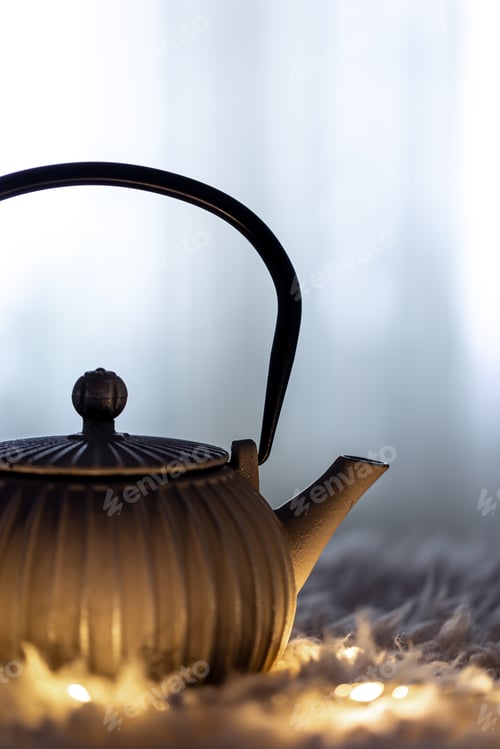 Preview: Teapot on a blurred background in the dark with garlands.