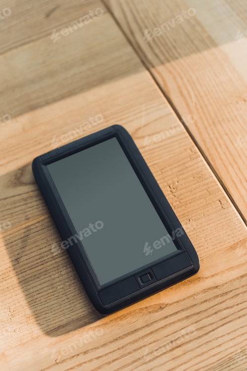 Preview: ebook with blank screen lying on wooden table