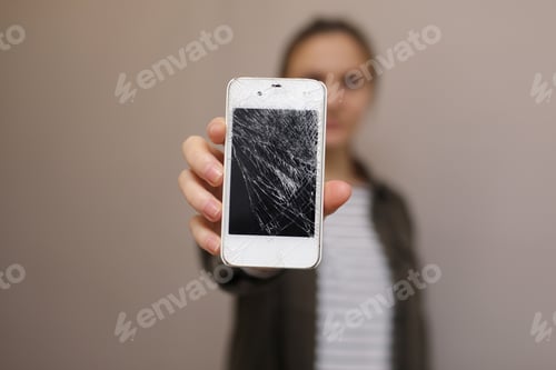 Preview: Frustrated young woman holding cellphone with broken screen glass. Phone display needs to repair.
