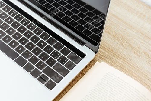Preview: close-up shot of laptop with opened book on wooden surface