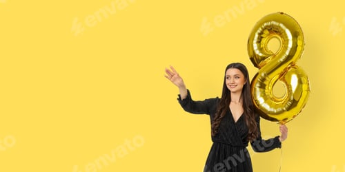 Preview: Young woman waves while holding a gold number 8 balloon