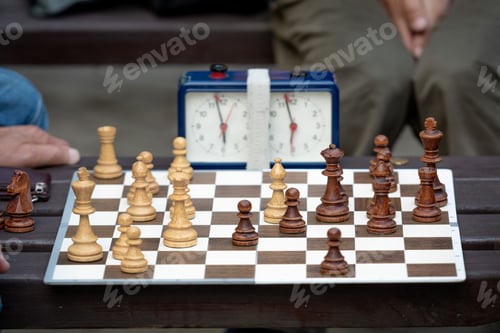 Preview: People sit in the park on benches and play chess.
