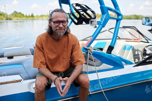 Preview: Smiling bearded man sitting on boat water sports outdoors