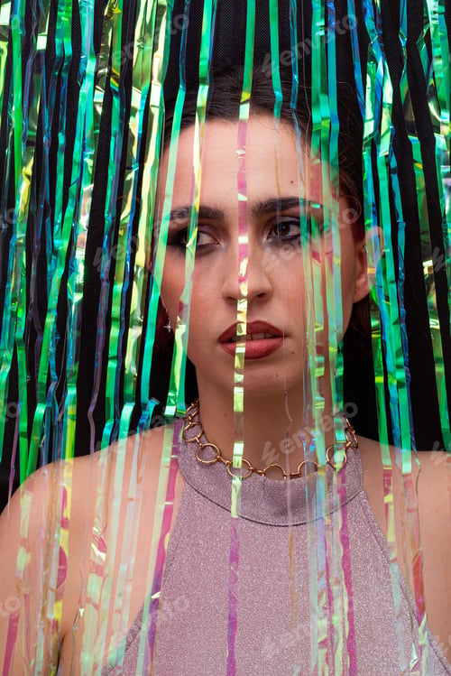 Preview: a woman posing in front of streamers of ribbons as she wears purple and green