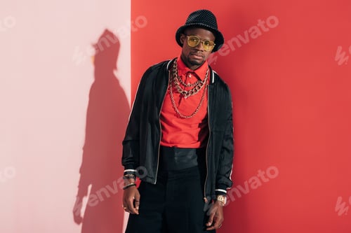 Preview: african american man in hat, sunglasses and jewellery posing in studio