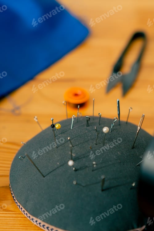 Preview: close-up in a sewing workshop pin cushion is completely stuffed with needles and pins