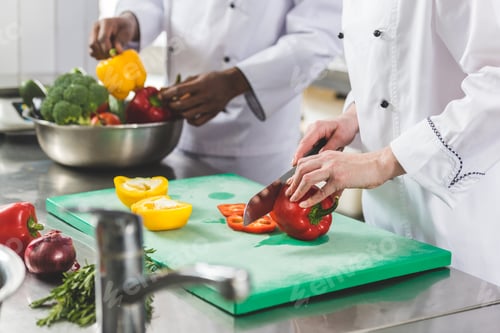 Preview: cropped image of chef cutting bell peppers at restaurant kitchen