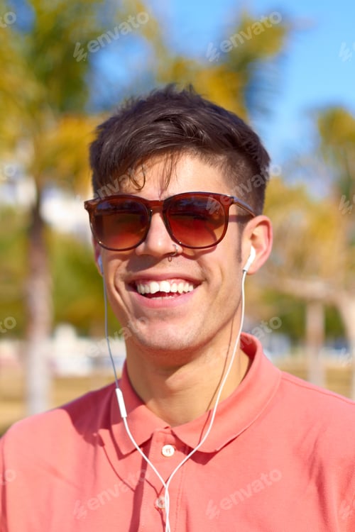 Preview: Summer, sunnies and some tunes. A happy young man listening to music in the sun.