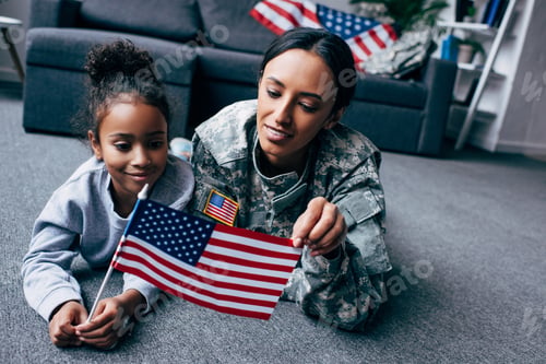 Preview: african american daughter and soldier in military uniform with american flag at home