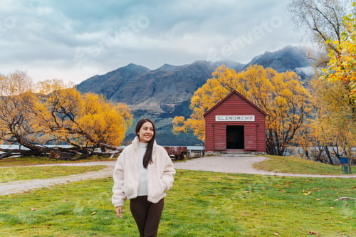 Preview: Asian woman traveling in Glenorchy with red boatshed by Lake Wakatipu on autumn at New Zealand