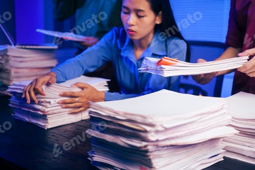 Preview: Three young businessmen work together in office at night, busy on their laptops,checking documents
