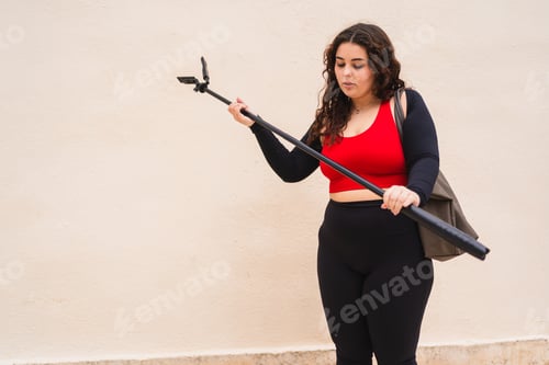 Preview: Content creator preparing her selfie stick for streaming outdoors