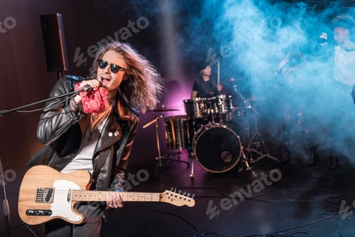 Preview: Male singer with microphone and rock and roll band performing hard rock music on stage