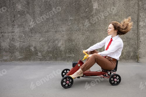 Preview: Funny businesswoman driving retro pedal car outdoor