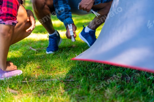 Preview: Campers pitching tent on campground, setting up campsite on green grass
