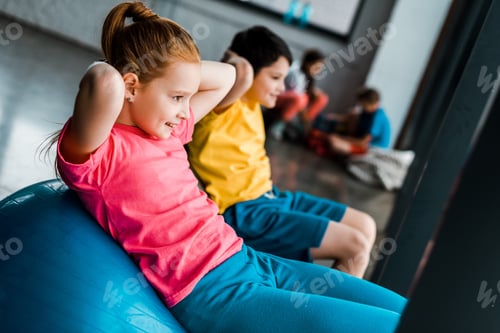 Preview: Cheerful kids doing abs exercise with fitness balls