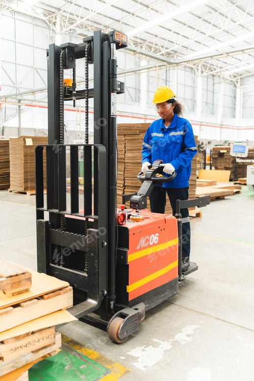 Preview: African American female worker driving forklift truck in heavy metal industrial factory
