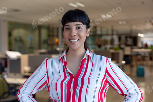 Preview: Portrait of happy young biracial female advisor with black bangs standing at modern workplace