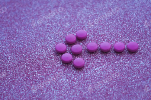 Preview: An arrow from pink medicines on the glittery background.